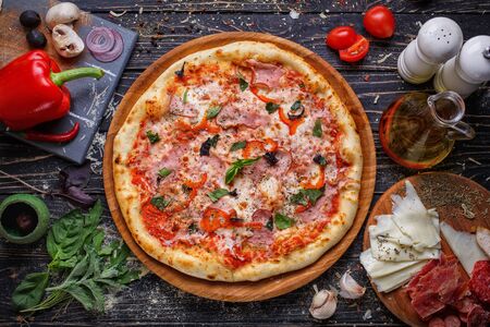 Top view of pizza with meat, tomatoes, cheese, basil on a wooden plate. Italy food. Ingredient composition for pizza. Flat lay.の写真素材