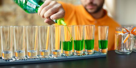 Barman preparing green cocktail. Green alcoholic drink in glasses on bar. Concept of elite alcohol.