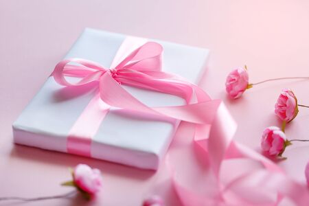 Spring decor from small pink roses. White gift box with a pink ribbon on a light background. Mother's Day.の写真素材