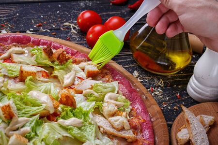 Unusual pizza with chicken meat, slices of white bread, cabbage, tomato paste and mayonnaise. The cook packs the olive oil. Clous up.の写真素材