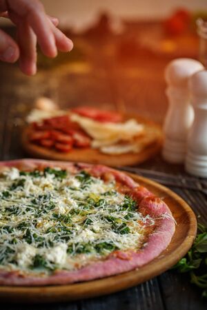 Chef's hand decorates a delicious hot pizza cheese. Pizza from pink doughの写真素材