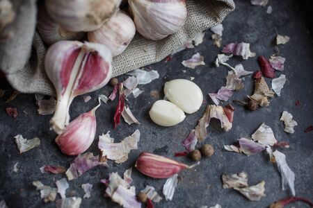 Garlic in burlap. Peeled garlic cloves, garlic bulb on a dark background. Healthy eating concept. Blurred background.の写真素材