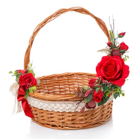 Decorated natural vine basket with high handle. Decor of red roses and lace ribbon on white background. Side viewの写真素材