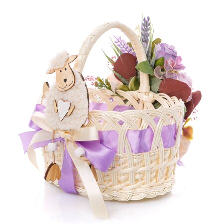Baby little Easter basket with lamb. Decor with various flowers and greens with purple ribbon on white background. Isolatedの写真素材