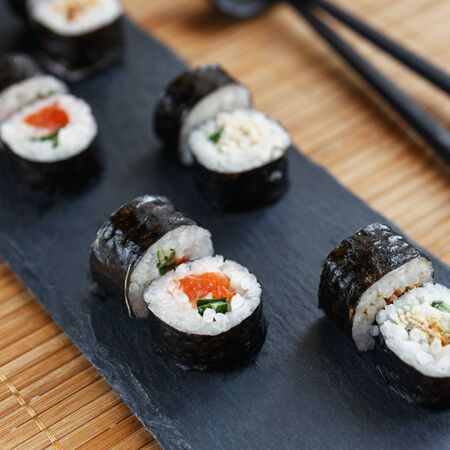 Sushi on a black stone board. Fresh set of sushi with salmon and avocado. Traditional Japanese cuisine.の写真素材