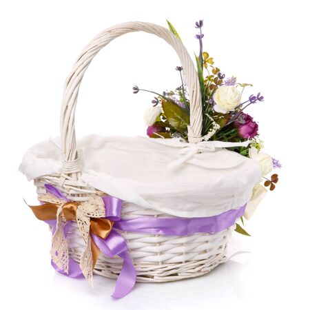 Wicker basket for Easter celebration. Color ribbon bow and lace and flower arrangement. Back view. On a white background.の写真素材