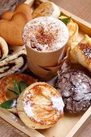 Cinnamon coffee and homemade chocolate cookies, strudel and mint cheeses. Handmade desserts and coffee in paper cup on brown rustic wooden background. Top view, close up.の写真素材