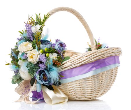 Brown wicker basket with floral decoration, decorative wooden bunny and ribbons on white background. The basket is decorated in in pastel colors before Easter. Provence style. Side view.の写真素材