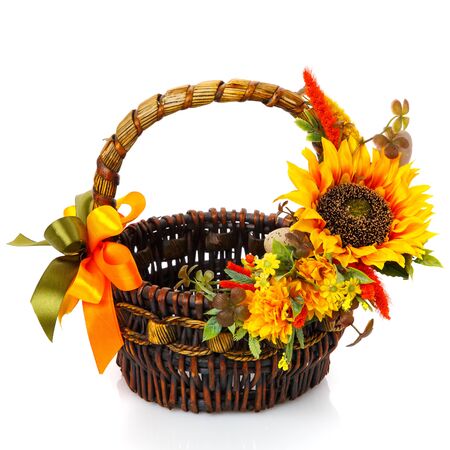 Original dark brown wicker basket with floral decoration on white background. Decor of yellow flowers and large sunflower flower. Ukrainian style Easter basket. Front view.の写真素材