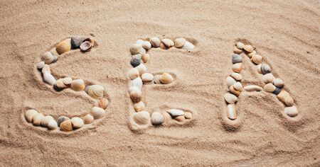 A beach with an inscription in English: sea. The letters are made by sea shells. Sea vacation.の写真素材