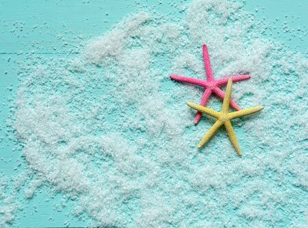 Two beautiful colored starfish lie on artificial sea foam on turquoise wooden background. Sea vacation concept. Place for text. Banner template.の写真素材
