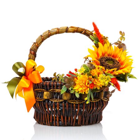 Original dark brown wicker basket with floral arrangements. Great scenery with yellow flowers, greenery and a large sunflower flower. Shopping cart in Ukrainian style. Isolated on white background. Side view.の写真素材
