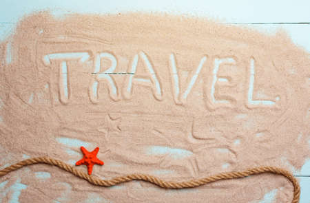 Inscription travel on the sand. Starfish and rope on summer background. Travel and vacation conceptの写真素材