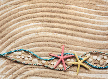 Starfish and colored ropes on a background of wavy sand. Souvenirs for travel, travel, leisure. Marine cruise theme. Top view with place for text. Sea, sand, beach.の写真素材