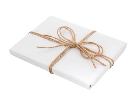Gift wrapped in white paper with a bow made of burlap thread on a white background.