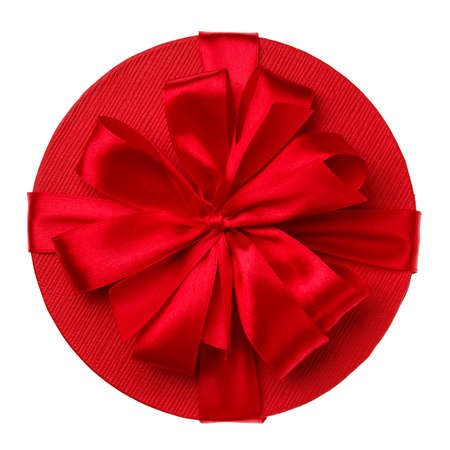 Round red gift box wrapped with big satin bow isolated on white background. Top view.の写真素材