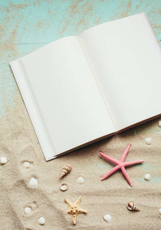 Summer template. Travel Planning. Notepad, small seashells, starfish on sand. Place for text on blank white notepad pages. Travel concept, top view.の写真素材