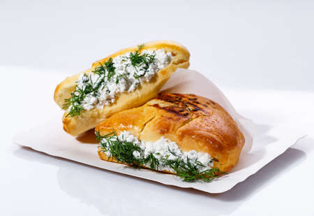 Fragrant muffin stuffed with cottage cheese and dill on a paper plate on a white background. Selective focus, close up.の写真素材