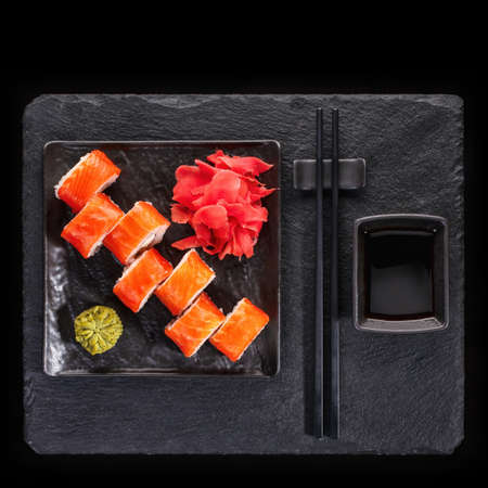 Japanese restaurant, sushi roll on black slate. Set with chopsticks, ginger and wasabi on a dark background. Top view.の写真素材