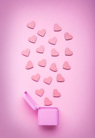 Pink round metal gift box with small wooden hearts on a delicate pink background. Top viewの写真素材