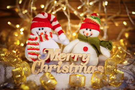 Smiling Christmas toys dressed in scarf and cap with text. Still life of Christmas toys wit garlandの写真素材