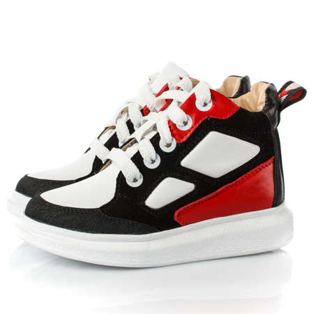 Kid's black and white sneakers for boy with red inserts isolated on white. Side view.の写真素材