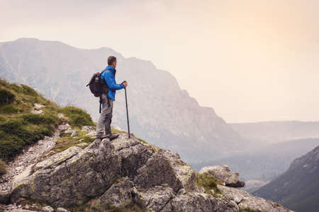 Hiker with backpack standing on top of a mountainの写真素材
