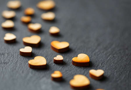 Beautiful little decorative wooden hearts on black background. Love concept. Selective focus.の写真素材