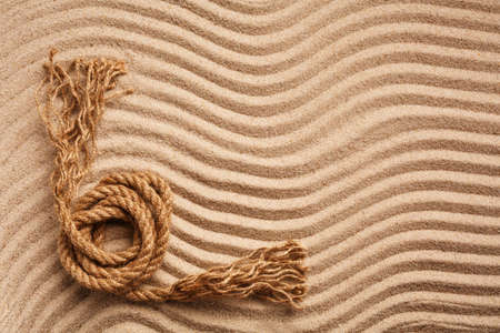 Sturdy marine rope on wavy texture sand. A place for text or for an advertising product. Top view. Banner template.の写真素材