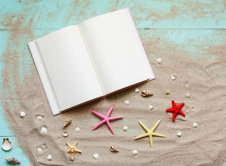 Summer background with notepad and seashells on sand on wooden turquoise background. Holiday...