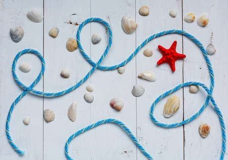 Red starfish, seashells and blue sea rope on turquoise wooden background. Top view.の写真素材