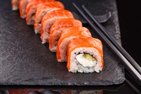 Beautiful Philadelphia rolls with salmon and cream cheese on a plate of black slate.の写真素材