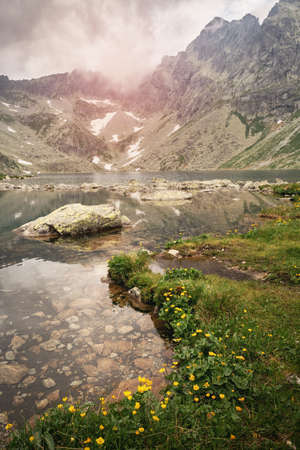 The lake is surrounded by the mountains which are reflected in the water. Hiking in the High Tatras during the summer holidaysの写真素材