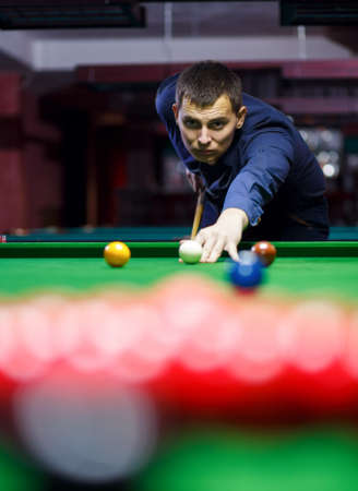young man lines up his shot as he breaks the balls for start game of billiardsの写真素材
