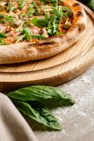 Crispy crust of Italian pizza close up. Basil leaves in front and fragrant pizza behind.の写真素材