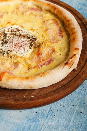 Breakfast pizza with egg on a blue wooden table with copy space.の写真素材