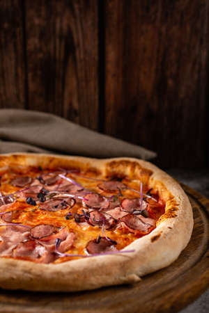 Delicious pizza on a wooden background close up. Pizza with meat, cheese and basil. Selective focus.の写真素材