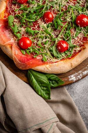 Pizza with arugula and cherry tomatoes on wooden board. Fresh homemade pizza.の写真素材