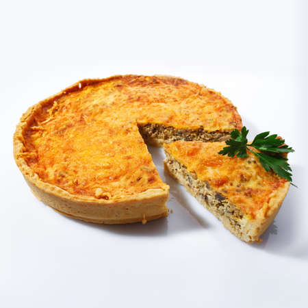 Homemade pie with champignons and cheese on a white background, side view. Spicy mushroom pie. Sliced piece decorated with greens and nuts.の写真素材