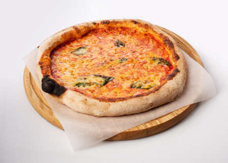 Top view of hot pizza on a wooden stand. Pizza Margarita. Tomato base and a lot of mozzarella, the taste of Dutch cheese and fresh basil.の写真素材