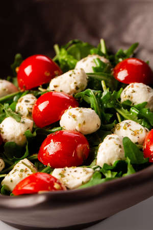 Caprese salad. Only fresh arugula, cherry tomatoes, juicy mini mozzarella and a dressing of oregano and olive oil are combined.の写真素材