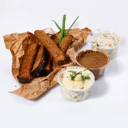 Crackers of black bread lie on kraft paper, mayonnaise and garlic sauce, meat pate, lard with dill on a white backgroundの写真素材