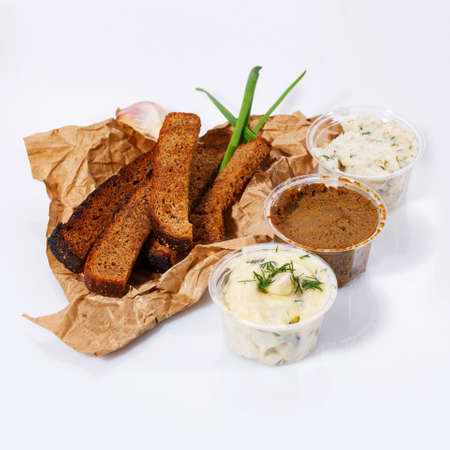 Crackers of black bread lie on kraft paper, mayonnaise and garlic sauce, meat pate, lard with dill on a white backgroundの写真素材