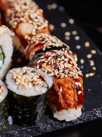 Sushi sashimi and maki sprinkled with sesame seeds on a stone plate on a dark background.の写真素材