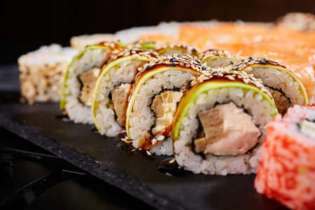 Sliced sushi rolls with crab meat and avocado drizzled with sauce and sprinkled with sesame seeds.の写真素材