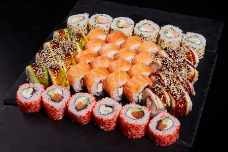 Sushi set of different rolls with different fillings on a slate of black stone.の写真素材