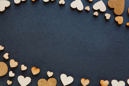 Wooden hearts are beautifully placed on a dark board. Place for text. Top viewの写真素材