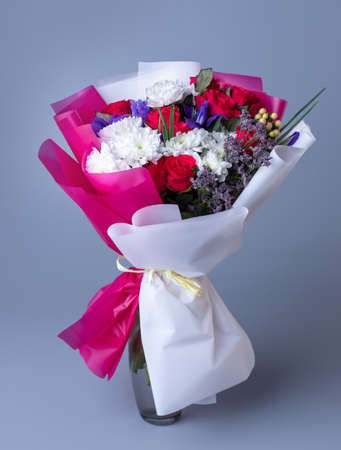 Bouquet of pink and white flowers wrapped in floral paper on a blue background.の写真素材