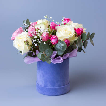 Bouquet of roses in a blue velor round gift box on a blue background.の写真素材