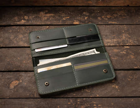 Leather green wallet with money and credit cards on old wooden backgroundの写真素材